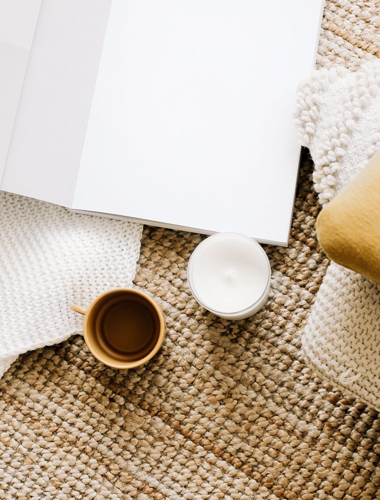 Coffee cup, candle and notebook on a woven rug, relaxing moment in a rental home.